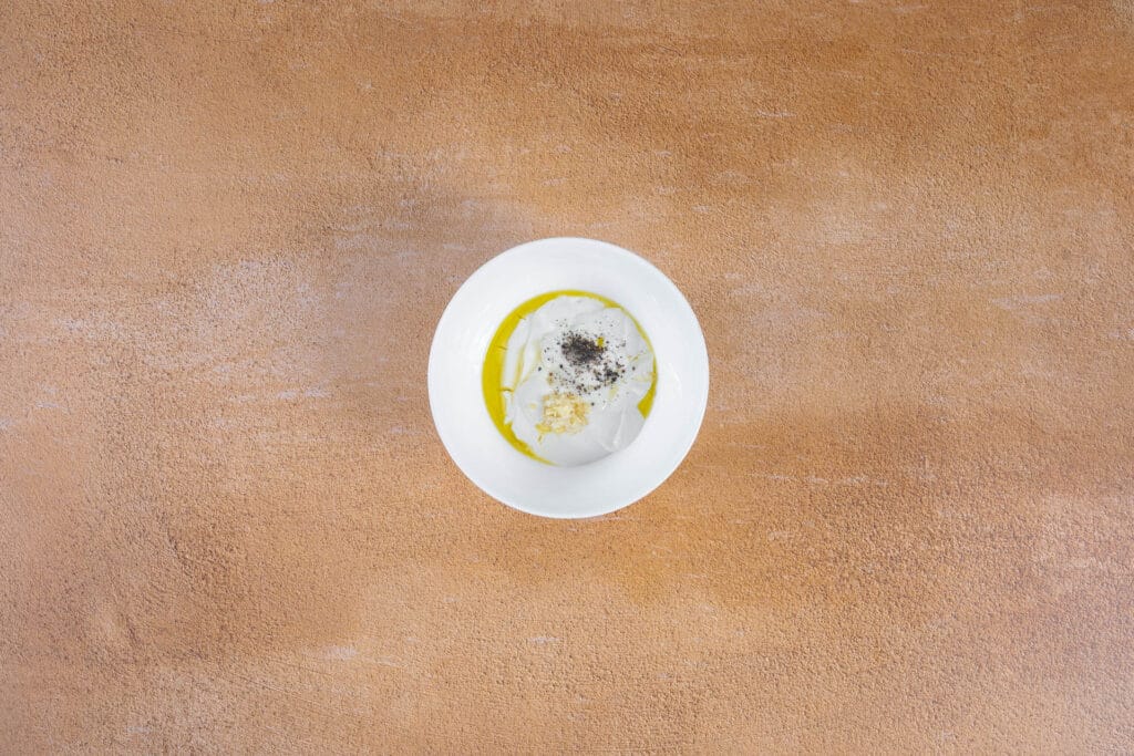 Veganes Tzatziki mit Joghurt, Knoblauch, Olivenöl und Pfeffer vor dem Verrühren