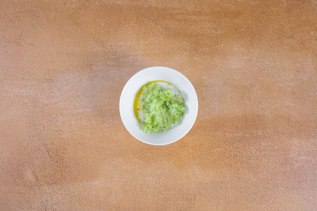 Ausgedrückte geraffelte Gurke wird unter das vegane Tzatziki gemischt