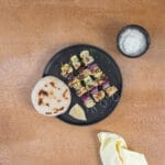 Griechische Tofu Souvlaki Spiesse mit Tzatziki und Pita auf einem schwarzen Teller