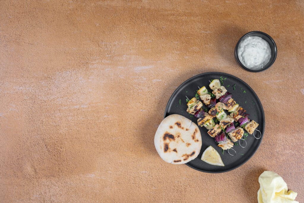 Gegrillte vegane Souvlaki mit Petersilie, Zitrone, Pitabrot und einer Schale Tzatziki