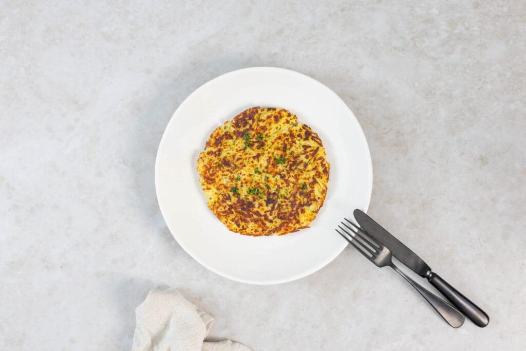 Vegane Rösti mit knuspriger Kruste, angerichtet mit Messer und Gabel