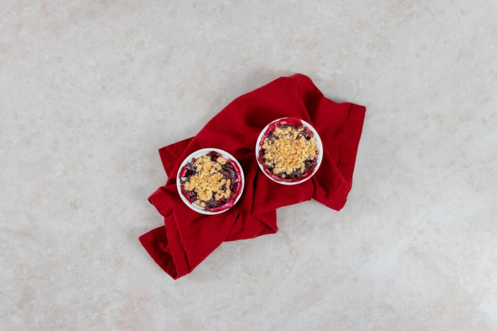 Zwei vegane Beeren-Crumbles auf roter Serviette, serviert als sommerliches Dessert
