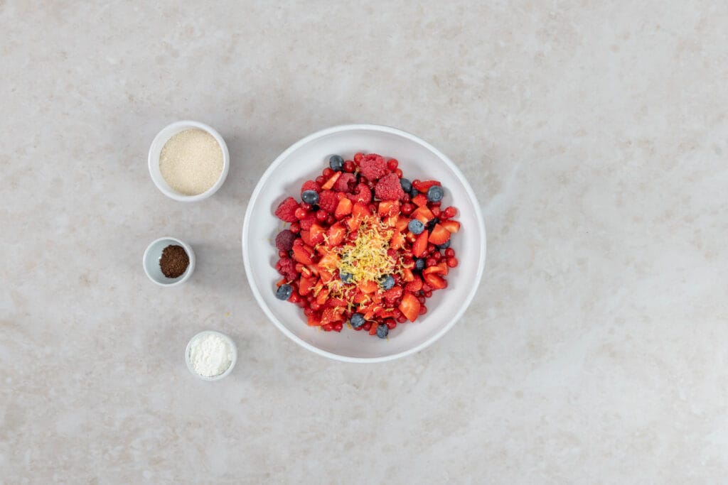 Gemischte Beeren mit frisch geriebenem Zitronenabrieb in einer weissen Schüssel