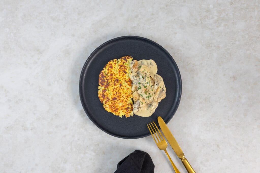 Portion veganes Zürcher Geschnetzeltes mit Rösti, Petersilie und goldenem Besteck