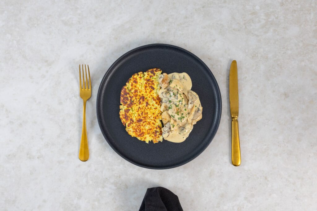 Veganes Züri Gschnätzlets mit knuspriger Rösti, serviert auf dunklem Teller