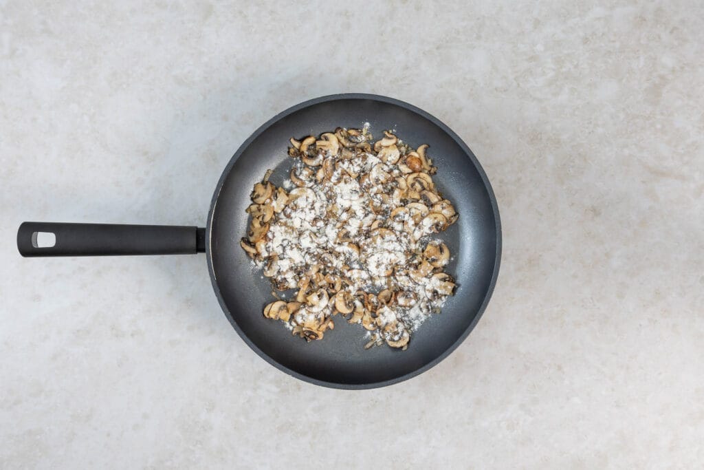 Die gedünsteten Champignons werden für die Sauce mit Mehl bestäubt