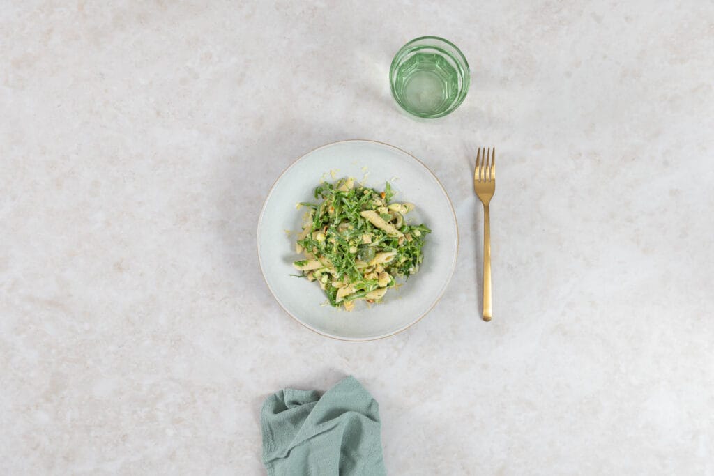 Green Goddess Pastasalat vegan angerichtet auf hellem Teller, sommerliches Gedeck von oben