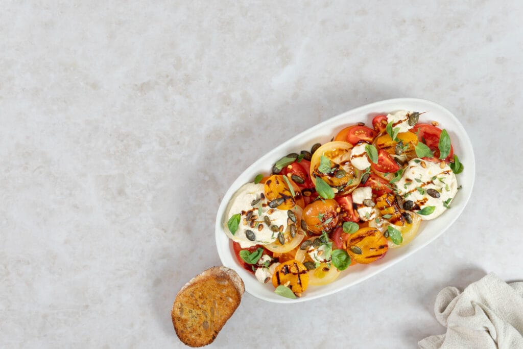 Veganer Aprikosensalat vom Grill mit bunten Tomaten, Ricottacreme, Kürbis- und Pinienkernen sowie Basilikum und Thymian