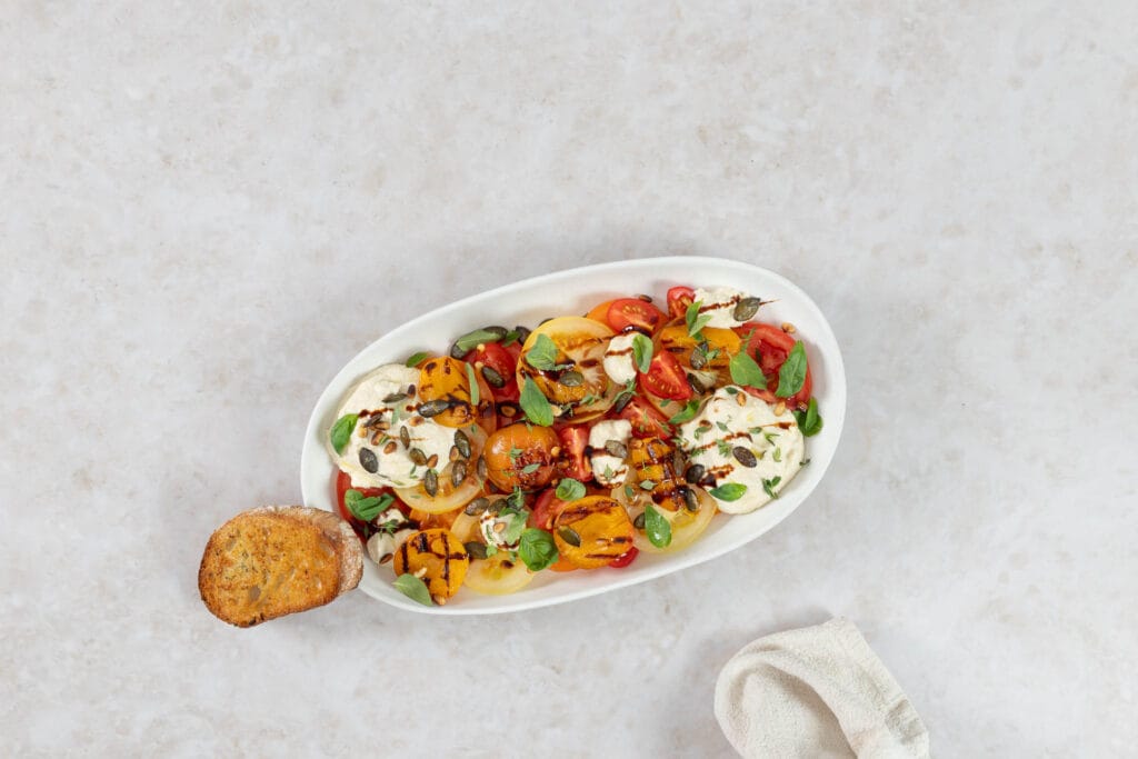 Grillierter Aprikosensalat mit veganer Ricottacreme, serviert mit einer Scheibe knusprigem Knoblauchbrot