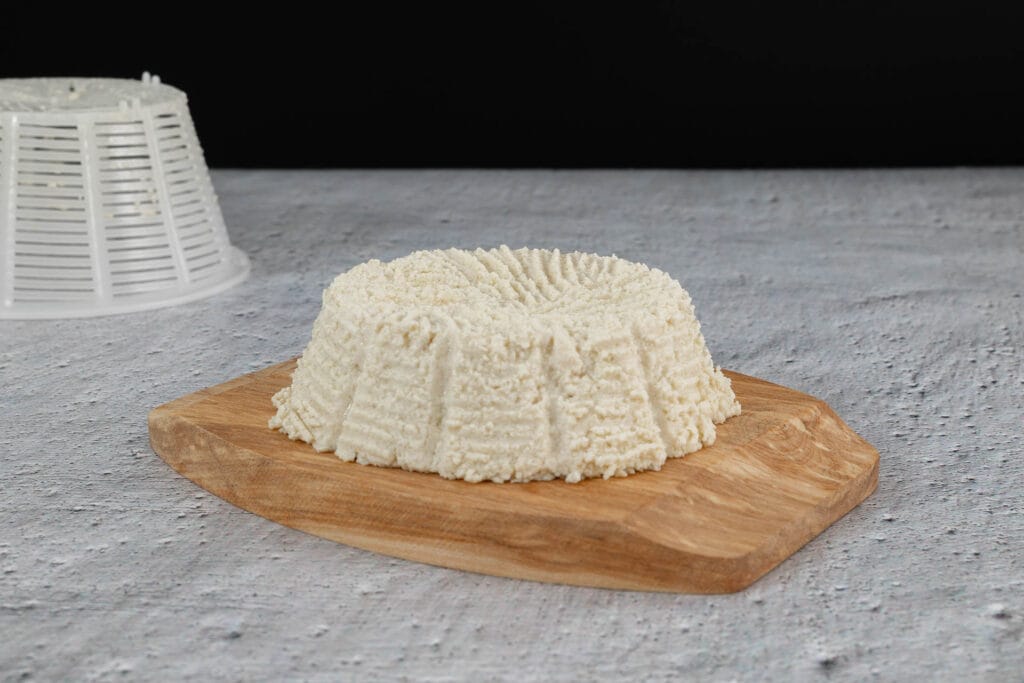 Geformter veganer Ricotta mit der Form im Hintergrund