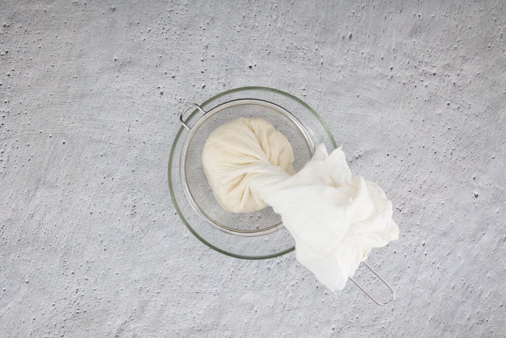 Ausgedrückter Seidentofu im Mulltuch über einem Sieb