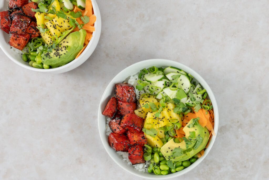 Nahaufnahme der veganen Poké Bowl mit gebackenem Wassermelonen-Thunfisch, Ananas, Avocado und schwarzem Sesam