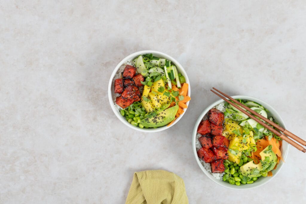 Zwei Schalen veganer Wassermelonen-Thunfisch Poké Bowl mit Ananas, frischem Gemüse und Sushi-Reis