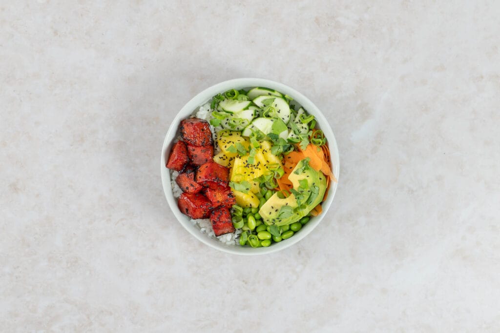 Vegane Poké Bowl mit Wassermelonen-Thunfisch, Avocado, Ananas, Edamame und Koriander von oben