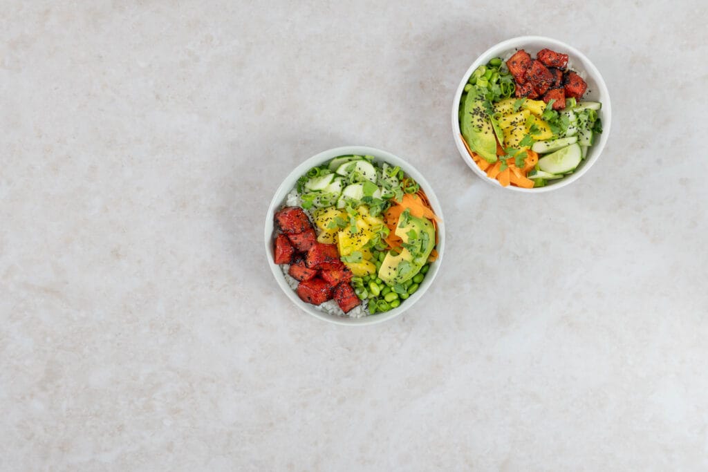 Zwei vegane Poké Bowls mit Wassermelonen-Thunfisch, Ananas und frischem Gemüse auf Sushi-Reis
