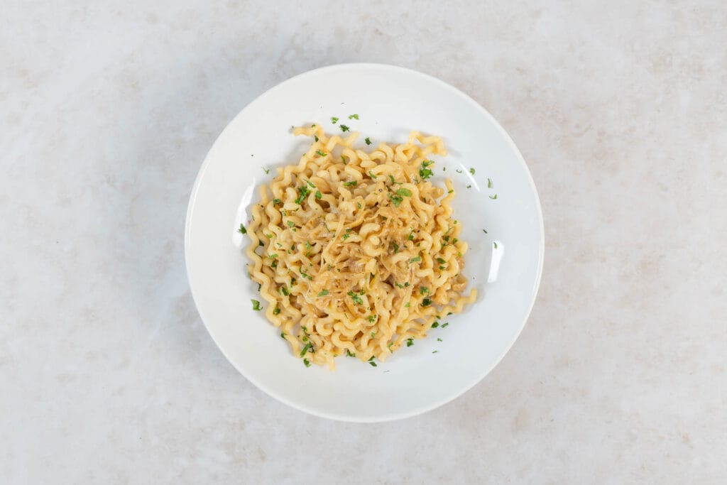 Teller mit karamellisierter Zwiebel-Pasta und frischer Petersilie von oben fotografiert