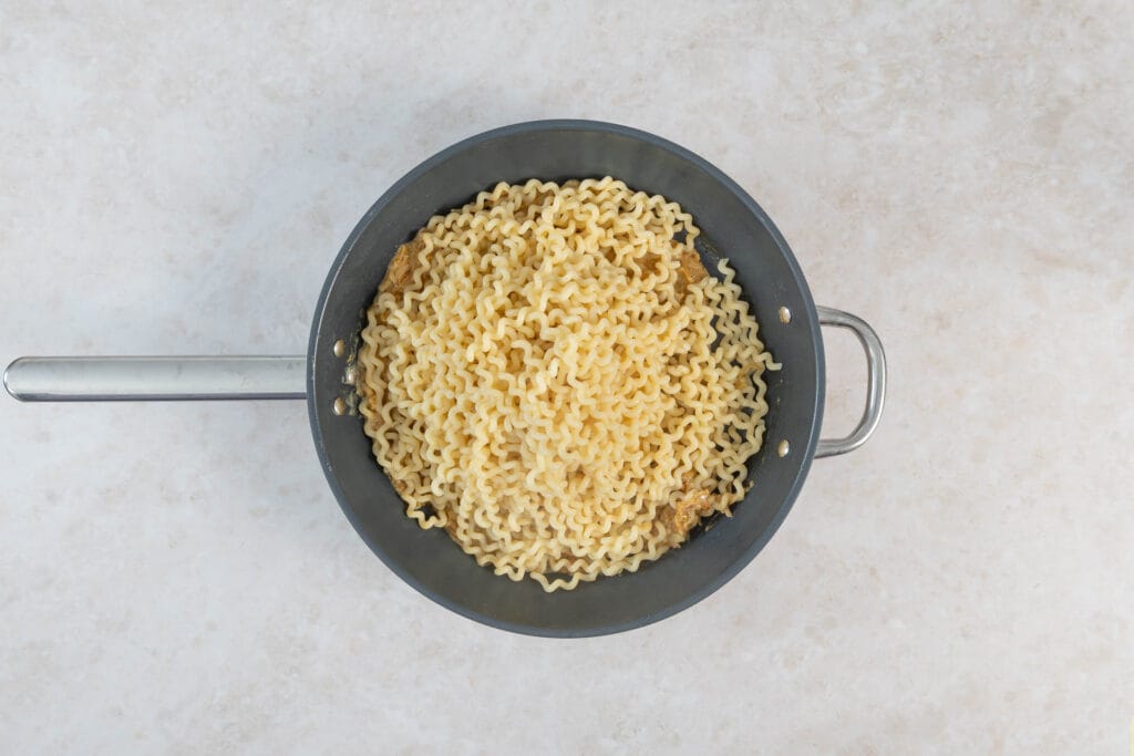 Al dente gekochte Fusilli Bucati Lunghi auf der Zwiebelsauce in der Bratpfanne