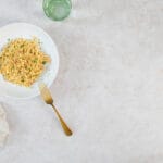 Vegane karamellisierte Zwiebel-Pasta mit Petersilie auf weissem Teller mit goldener Gabel