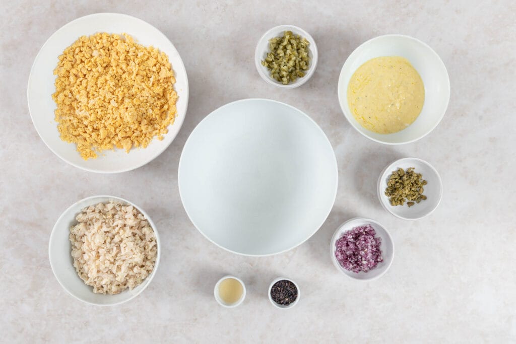 Alle vorbereiteten Zutaten für veganen Thonsalat in Schalen rund um eine grosse Salatschüssel