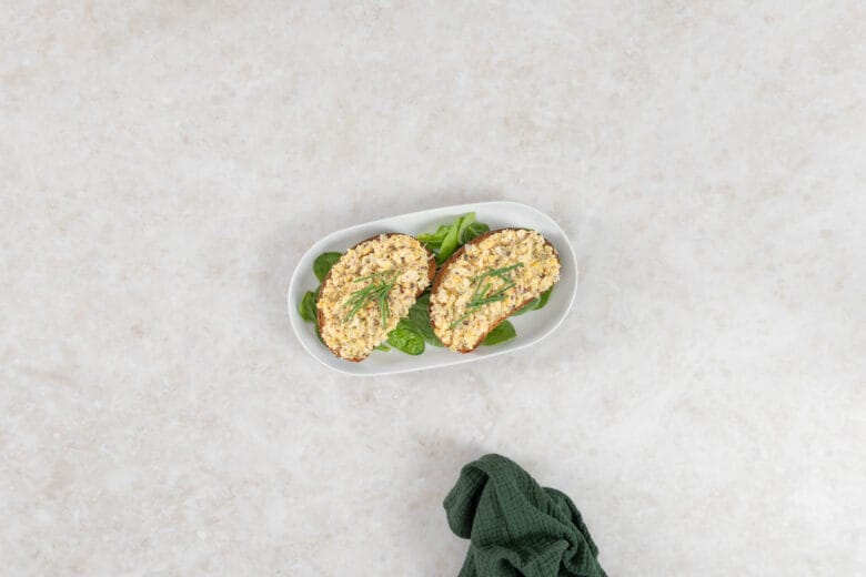 Veganer Thonsalat auf zwei Scheiben Ruchbrot mit Schnittlauch auf Salatblättern