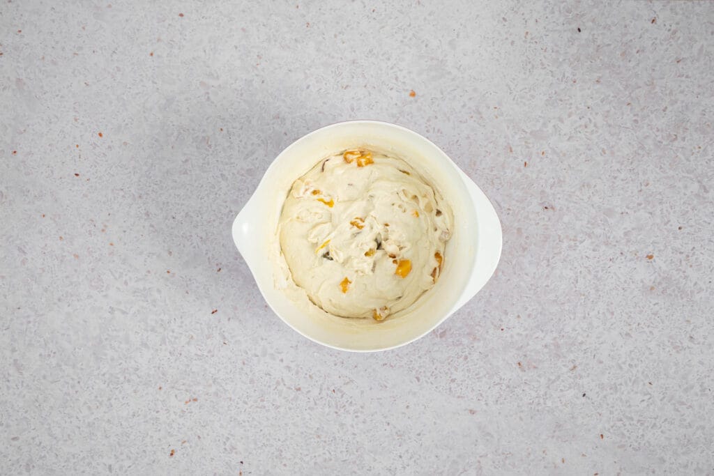 Fruchtsalat mit der Gabel unter den veganen Cake-Teig gehoben