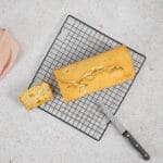 Veganer Fruchtcocktail-Kuchen auf dem Auskühlgitter, daneben eine abgeschnittene Scheibe und ein Messer
