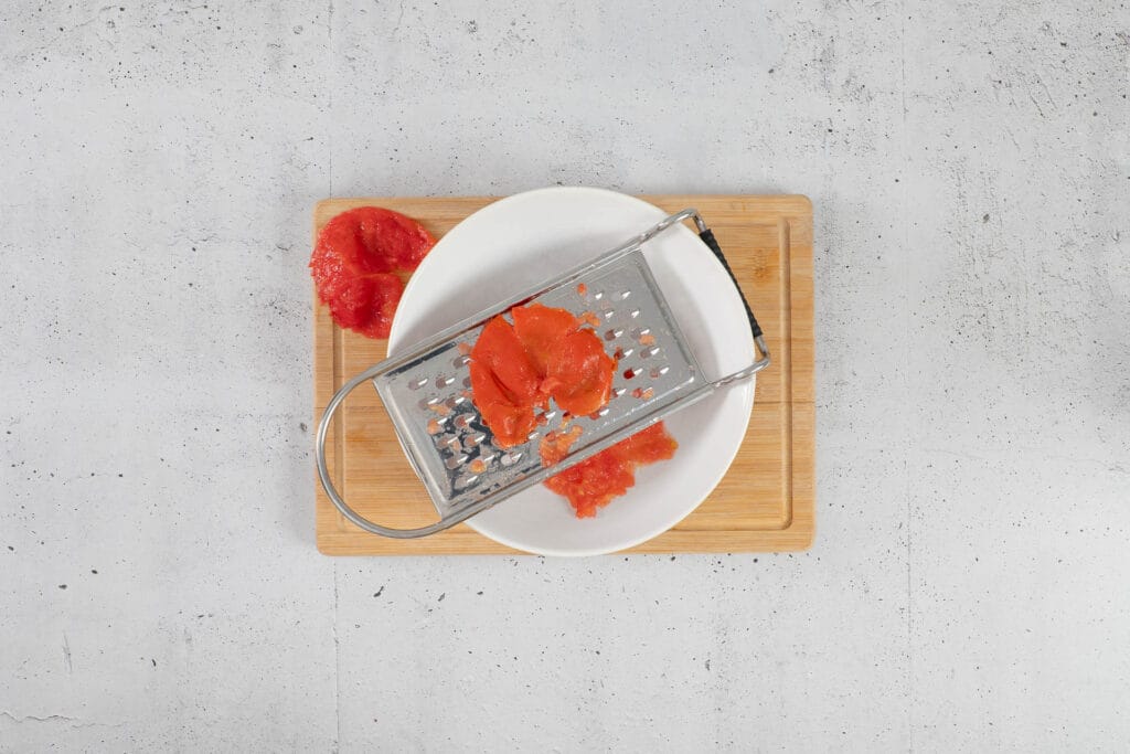 Tomatenfruchtfleisch auf der Röstiraffel gerieben, nur die Schale bleibt übrig