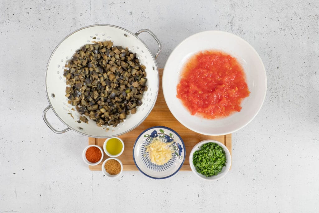 Vorbereitete Zutaten für Zaalouk mit gekochten Auberginen, geriebenen Tomaten, Knoblauch, Kräutern und Gewürzen