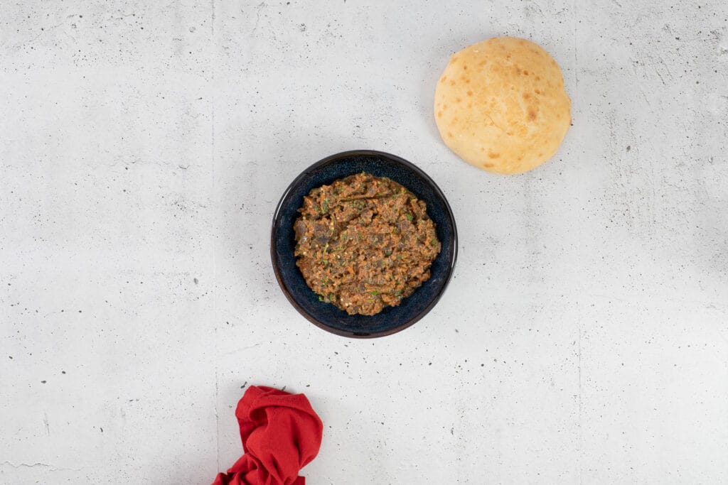 Zaalouk in einer dunkelblauen Schale mit Fladenbrot und roter Serviette