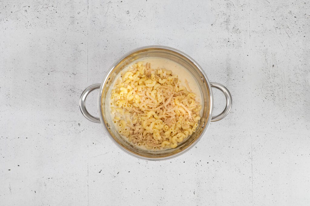 Gekochte Hörnli und restlicher geriebener Käse werden unter die vegane Käsesauce gemischt